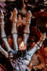 Halloween Candlestick.Scary autumn atmosphere. Skeleton Hand Holding Candle in Autumn...