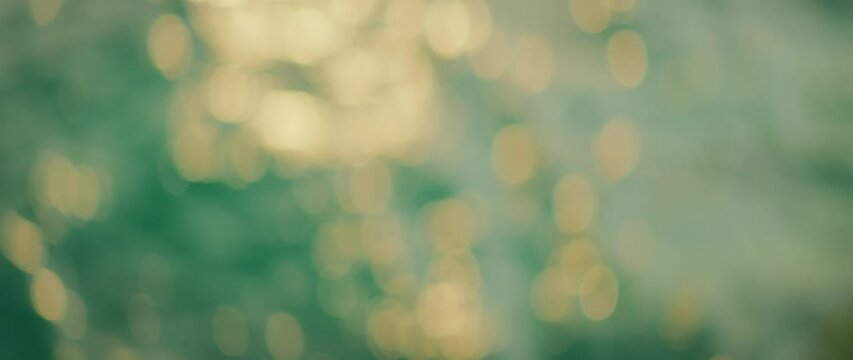 Out-of-focus golden sunlight reflecting on green sea water during sunset light