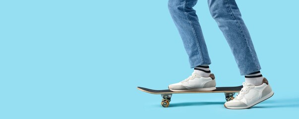 Legs of young guy with skateboard on blue background with space for text © Pixel-Shot