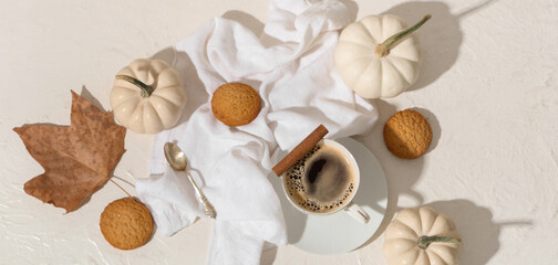 Cup of tasty pumpkin coffee with autumn decorations and cookies on grunge white background