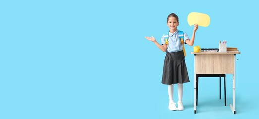 Happy schoolgirl holding blank speech bubble on blue background with space for text