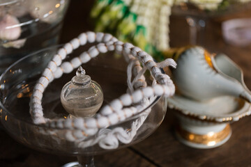 wedding concept, decorative glass bowl with beads and vintage items on wooden table