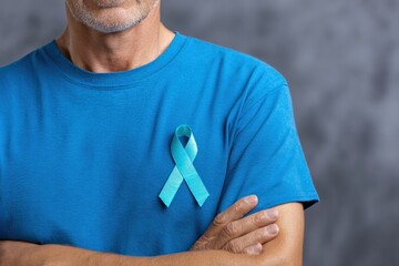Senior man is wearing teal ribbon on blue shirt to support sexual assault awareness and prevention