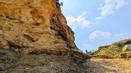 Eroded Cliff Face Under Blue Sky with Clouds Geological Formation.