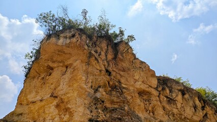 Eroded Cliff Face with Sparse Vegetation Against a Cloudy Sky.