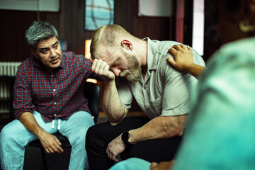 Depressed man receiving support during group therapy session