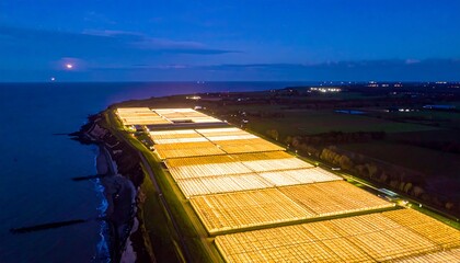 Obraz premium Illuminated greenhouses at night by the sea