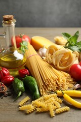 Different types of pasta and ingredients on wooden table, closeup