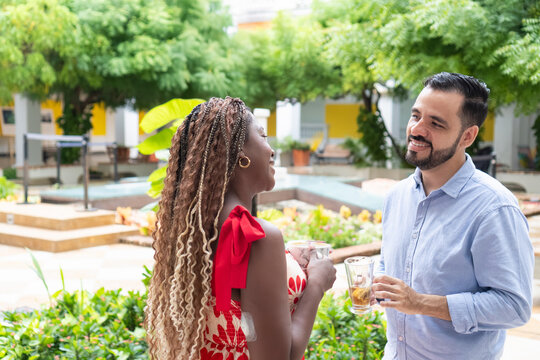 Cheerful interracial couple enjoying drinks and conversation in tropical garden