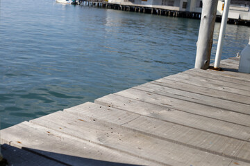 Fototapeta premium Wooden pier planks extending over calm blue water.