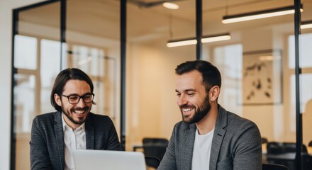 Two business men having a discussion while looking at a laptop in an office
