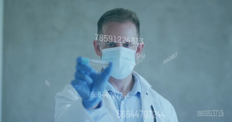 Examining scientist in lab coat, mask and gloves holding test tube in lab with numeric overlays