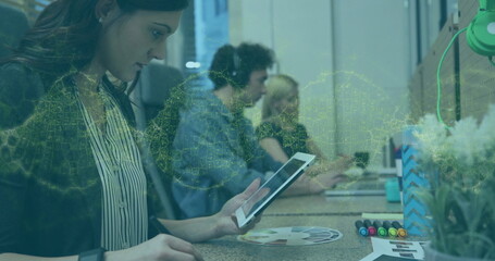 Leaning mature graphic designer sketching on tablet at shared desk, with color swatches, copy space