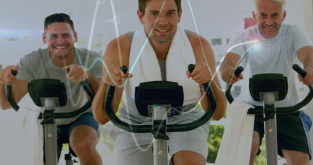 Pedaling center rider wearing sleeveless shirt with towel around neck in gym with stationary bikes
