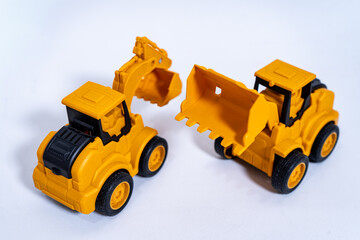 Two yellow toy excavators resting on white background