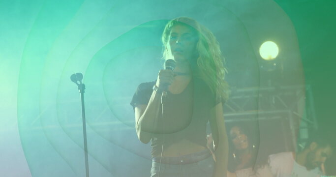Singing lead singer holding wired microphone at concert stage, with spotlights fog haze truss - Powered by Adobe