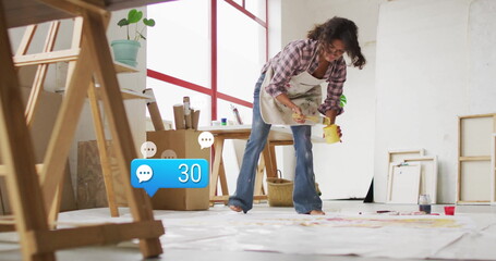 Artist painting canvases wearing apron in art studio, with paintbrush yellow paint jar copy space