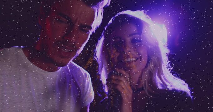 Performing adult man and woman singing on club stage, with microphone, stage light and sparkles