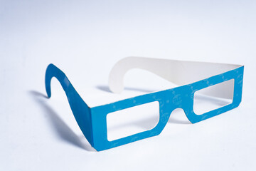 Blue and white cardboard 3d glasses resting on white background