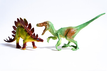 Velociraptor attacking stegosaurus dinosaur toy on white background