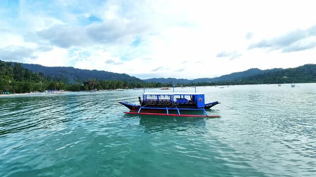 Filipino outrigger boat on tranquil water, surrounded by serene tropical scenery of Palawan.