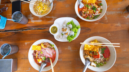 Tasty bowls of noodle soup filled with fresh ingredients sit on a rustic wooden table. Dumplings arranged on a plate provide additional flavor options for diners