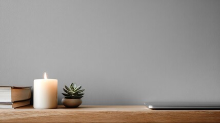 Minimalist scene with candle, plant, books, and laptop on a wooden shelf