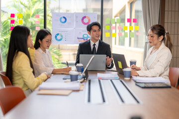 Business team meeting in modern office analyzing charts on sticky notes and laptops