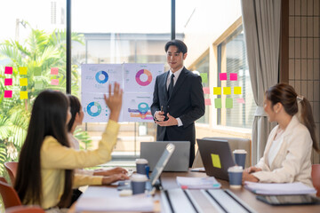 Businessman leading corporate meeting with charts and asking for questions