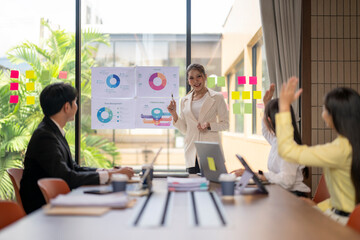 Asian businesswoman leading meeting with charts and pie graphs, using sticky notes in office