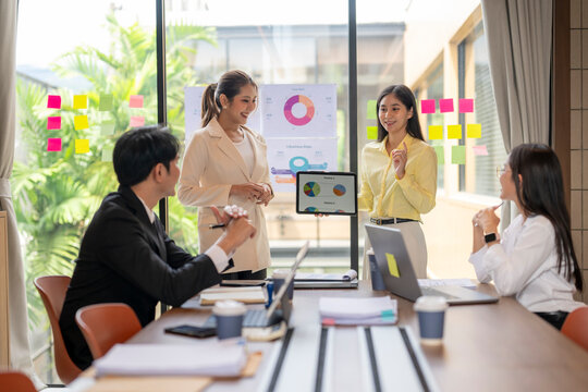 Asian businesswomen showing pie charts on tablet during office meeting - Powered by Adobe