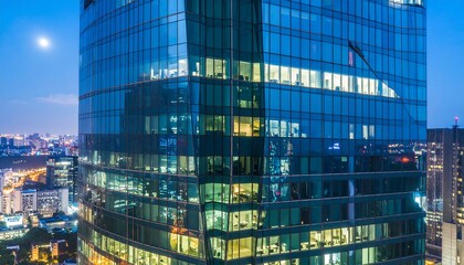 Fototapeta premium Modern Glass Skyscraper Illuminated at Night with Lit Windows.