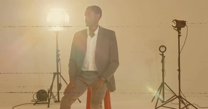 Man raising hand to adjust lapel and shifting gaze while glancing at wristwatch under studio lights
