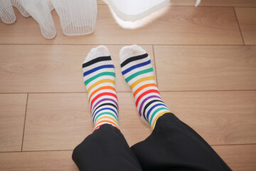 Colorful striped socks worn indoors on wooden floor