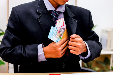 Businessman's Hands Place Colorful Indonesian Rupiah Into a Yellow Envelope Over a Contract