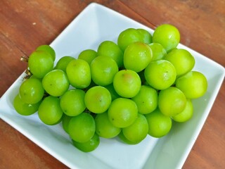 Fresh green grapes on a white plate, showcasing their juicy texture and vibrant color