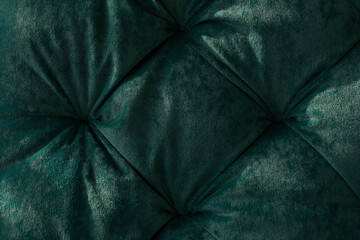 Close-up of the soft surface of the furniture made of quilted pile velour in folds of emerald...