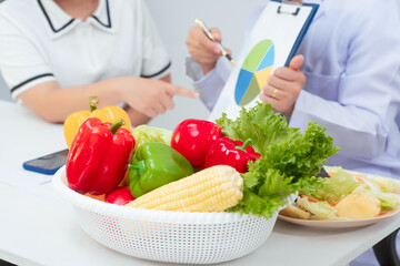 Professional Asian female nutritionist giving nutritional counseling to female patient sitting at clinic table discussing diet, health goals, meal plans and strategies for long-term wellness