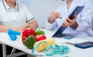 Professional Asian female nutritionist giving nutritional counseling to female patient sitting at clinic table discussing diet, health goals, meal plans and strategies for long-term wellness
