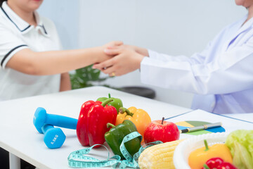 Professional Asian female nutritionist giving nutritional counseling to female patient sitting at clinic table discussing diet, health goals, meal plans and strategies for long-term wellness