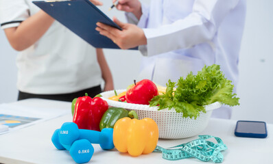 Professional Asian female nutritionist giving nutritional counseling to female patient sitting at clinic table discussing diet, health goals, meal plans and strategies for long-term wellness