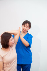 Young Asian nurse assisting middle-aged female patient on a couch doing physical therapy, focusing...