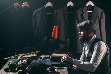 Tailor adjusting a classic suit. Professional dressmaker working in a stylish atelier. Bearded man sewing a jacket. Tailor crafting mens fashion. Tailoring process. Tailored jacket. Tailor man in