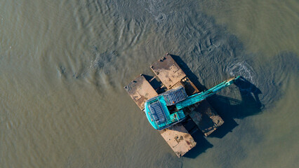 Aerial Photo of Aquatic Excavator with Floating Equipment Clearing Muddy Shoreline and River Estuary in the Afternoon