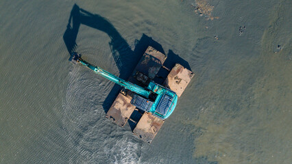 Aerial Photo of Aquatic Excavator with Floating Equipment Clearing Muddy Shoreline and River Estuary in the Afternoon