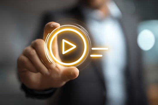 A person in a suit interacts with a glowing digital play button icon, symbolizing media, video playback, or digital content in a modern, blurred background setting
