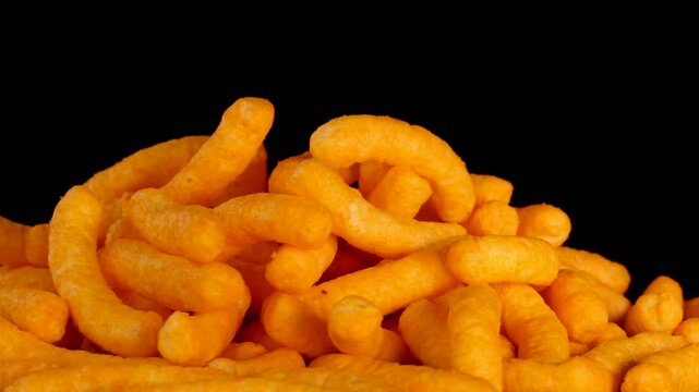 Rotating Pile of Cheese Puffs Snack on Black Background