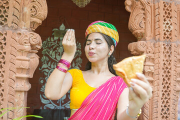 Young happy indian woman wearing sari and turban enjoy samosa street food of india.