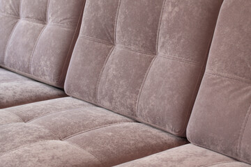 Close-up of pink quilted velour sofa. Soft furniture for relaxation covered with dusty rose plush...