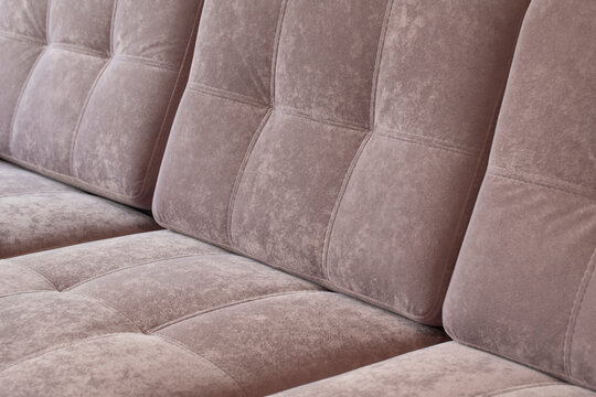 Close-up of pink quilted velour sofa. Soft furniture for relaxation covered with dusty rose plush material.